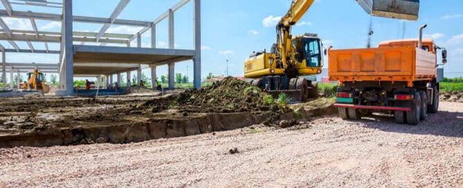 Excavator Filling A Dumper Truck With Soil At Construction